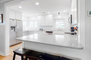 A modern kitchen with white cabinetry, a large island, and a built-in dishwasher. - Oxford Lodge (Lake Junaluska)