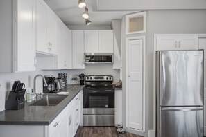 A modern kitchen with white cabinets, stainless steel appliances, and a built-in oven. - Historic Cap Hill Oasis w/View | Dogs Stay Free! (Seattle)