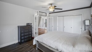 Une chambre à coucher comprenant un lit, une commode, un ventilateur de plafond et une armoire.