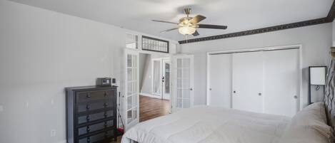 A bedroom with a bed, a dresser, a ceiling fan, and a wardrobe.