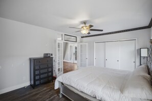 A bedroom with a bed, a dresser, a ceiling fan, and a wardrobe. - Upstairs Loft on Capitol Hill Home (Seattle)