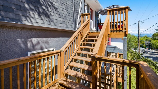 Un escalier en bois mène à une terrasse d’où l’on peut admirer une rue et des montagnes.