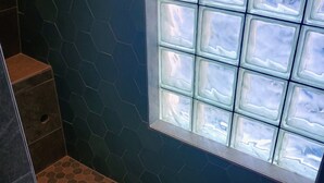 Une salle de bain avec un sol carrelé de motifs hexagonaux, une fenêtre à verre dépoli et un espace douche.
