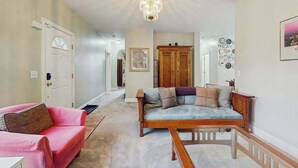 A hallway with a wooden bench, a pink sofa, and a wooden cabinet. - Tranquil Dog- Friendly Riverfront Home with Fill Kitchen and WIFI (Arden)