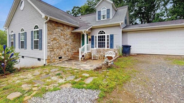 A two-story house with a stone facade, a front porch with a bench, and a garage. - Tranquil Dog- Friendly Riverfront Home with Fill Kitchen and WIFI (Arden)