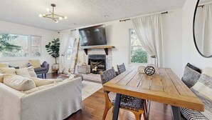 Een ruime woonkamer met een open haard, een eettafel en een bank.