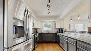 Een moderne keuken met roestvrijstalen apparatuur, donkere kastjes en een houten vloer.