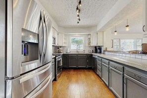 A modern kitchen with stainless steel appliances, dark cabinets, and a wooden floor. - Charming 4BR retreat with Full Kitchen, Wifi and Patio | Pet-friendly (Arden)