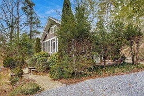 A house surrounded by dense forest, with a gravel driveway leading to the entrance. - Bearcat Cottage (Lake Junaluska)