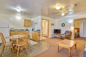A compact living space with a dining area, kitchen, and a TV.