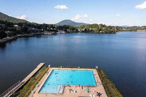 A swimming pool with a view of a lake and mountains in the background.