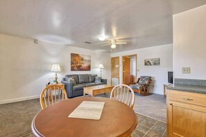 A living room with a dining table, sofa, chairs, and artwork on the walls.