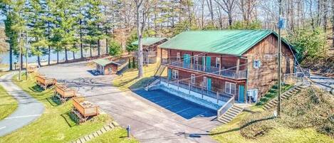 A cabin with a green roof, a covered porch, and a small dock.
