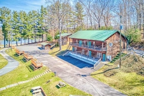 A cabin with a green roof, a dock, and a small boat.
