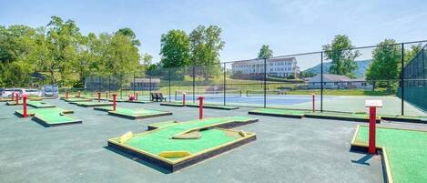 An outdoor golf driving range with multiple tee boxes and a netted area.
