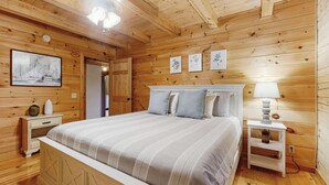 Een slaapkamer met houten lambrisering, een bed, nachtkastjes en wanddecoratie.