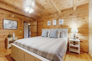 Ein Schlafzimmer mit Holzwänden, einem Bett, Nachttischen und Wandbildern.