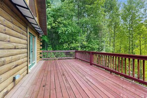 Eine Holzterrasse mit roter Geländer, umgeben von dichtem Grünwerk.