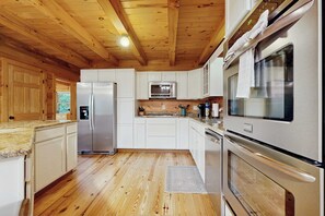 Eine moderne Küche mit Holzbalkendecke, Edelstahlgeräten und weißen Schränken.