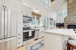 A modern kitchen with stainless steel appliances, a large island, and a stone fireplace.