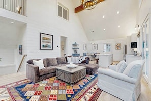 A spacious living room with a large sectional sofa, a coffee table, and a colorful rug.