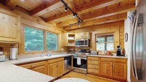 Eine Holzhütte mit Küche, inklusive großer Kochinsel, integriertem Mikrowellenherd, Backofen und Kühlschrank.