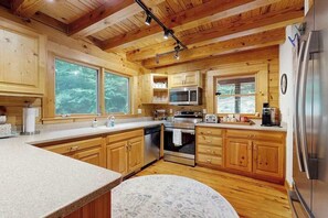 Eine Holzhütte mit Küche, inklusive großer Kochinsel, integriertem Mikrowellenherd, Backofen und Kühlschrank.