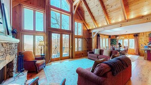 Un salón espacioso con chimenea de piedra, ventanas amplias y vigas de madera.