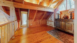 Interior de madera con techo alto, una escalera y una vista por una ventana.