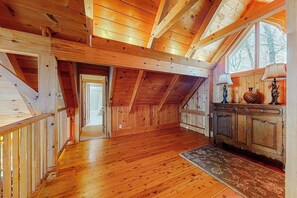 A wooden interior with a high ceiling, a staircase, and a view through a window. - Updated mountain view cabin with vaulted ceilings, large deck, & chef's kitchen (Sapphire)