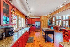 A spacious kitchen with wooden cabinets, a central island, and a dining area. - Updated mountain view cabin with vaulted ceilings, large deck, & chef's kitchen (Sapphire)