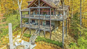 Une cabane en rondins à plusieurs étages, dotée de balcons et entourée de forêt.