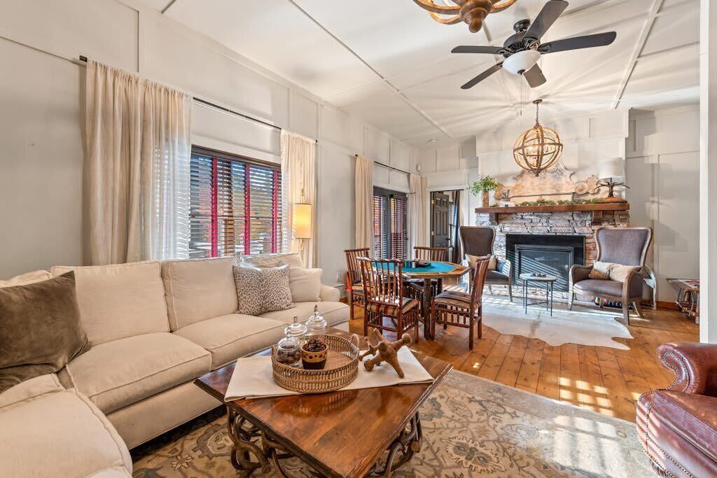 A living room with a sofa, a coffee table, a fireplace, and a ceiling fan.