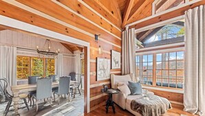 Un intérieur en bois comprenant un coin repas, un canapé et de grandes fenêtres.