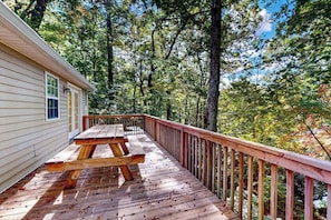 A wooden deck with picnic tables, surrounded by trees. - Sapphire Valley Community home with resort amenities & balconies - near skiing (Sapphire)