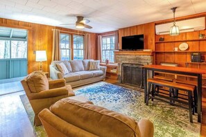 A living room with a sofa, chairs, a fireplace, a television, and a dining table. - Charlotte Cabin (Waynesville)