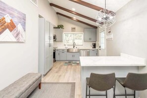 A modern kitchen with a central island, grey cabinetry, and a pendant light. - Contemporary dog-friendly mountain home with firepit, grill, enclosed backyard (Swannanoa)