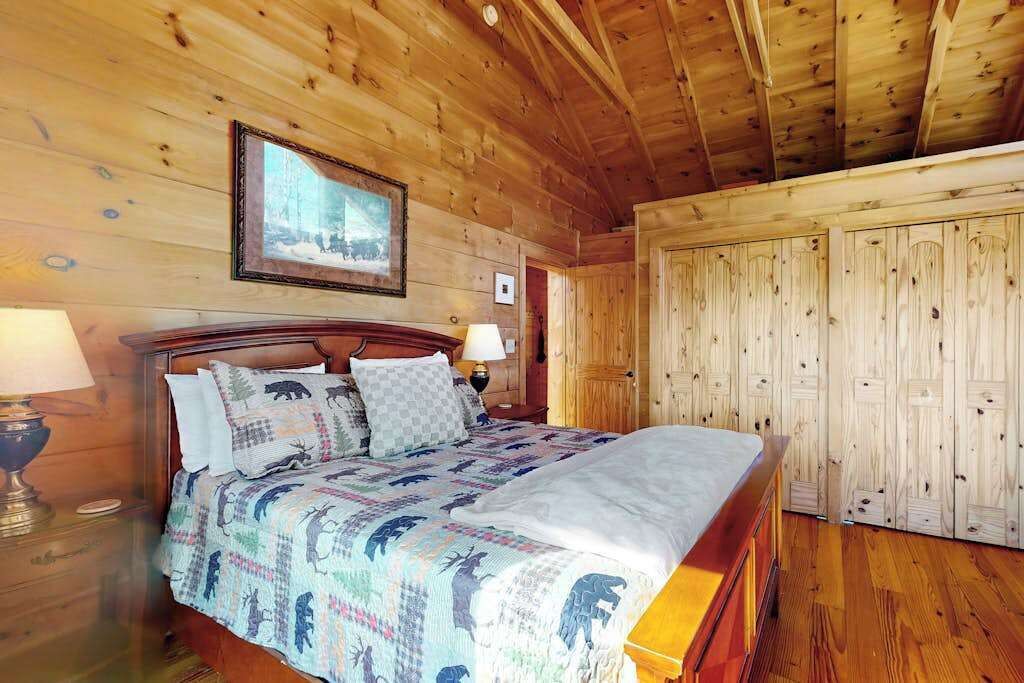 A wooden-paneled room with a bed, a framed picture on the wall, and a wardrobe.