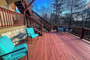 Eine Holzterrasse mit Außenmöbeln und einer Treppe zu einer erhöhten Ebene.