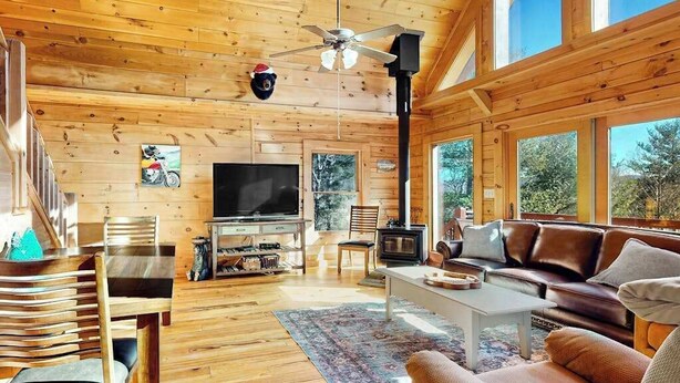 Ein Holzinnenraum mit Fernseher, Kamin, Sofa und Deckenventilator.