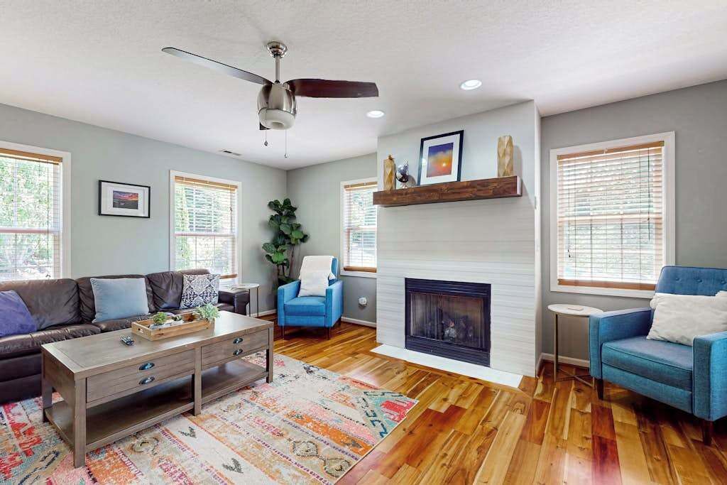 A living room with a fireplace, a ceiling fan, and a blue armchair.
