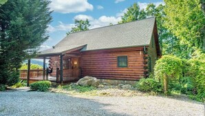 A log cabin with a porch, surrounded by trees and a gravel driveway. - Luxurious log cabin w/stunning views, WiFi, hot tub + 15 mins to Black Mountain (Old Fort)