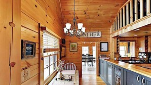 A wooden cabin interior with a dining area, kitchen, and a sign reading 'GATHER'. - Luxurious log cabin w/stunning views, WiFi, hot tub + 15 mins to Black Mountain (Old Fort)