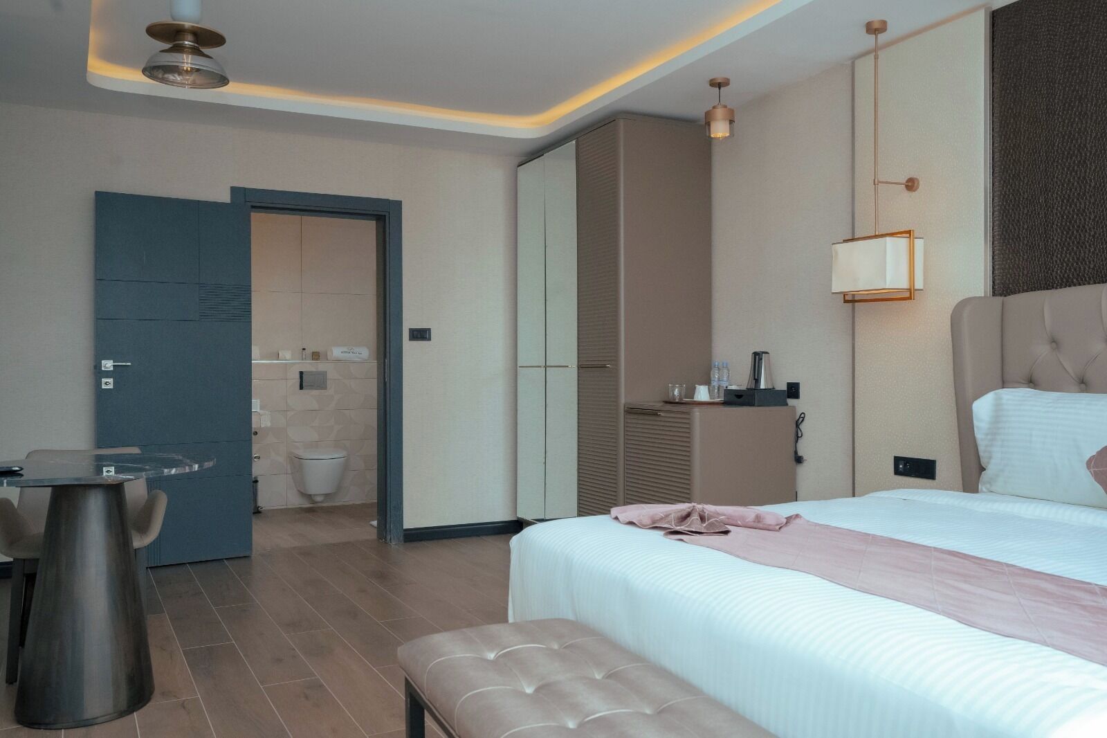 A hotel room with a bed, bedside table, and a small desk with a chair.