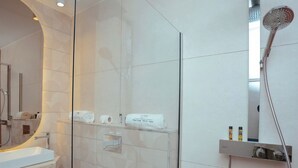 A modern bathroom with a glass shower enclosure, a large mirror, and a marble countertop.