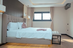 A modern bedroom with a large bed, a bedside table, and a window with curtains.