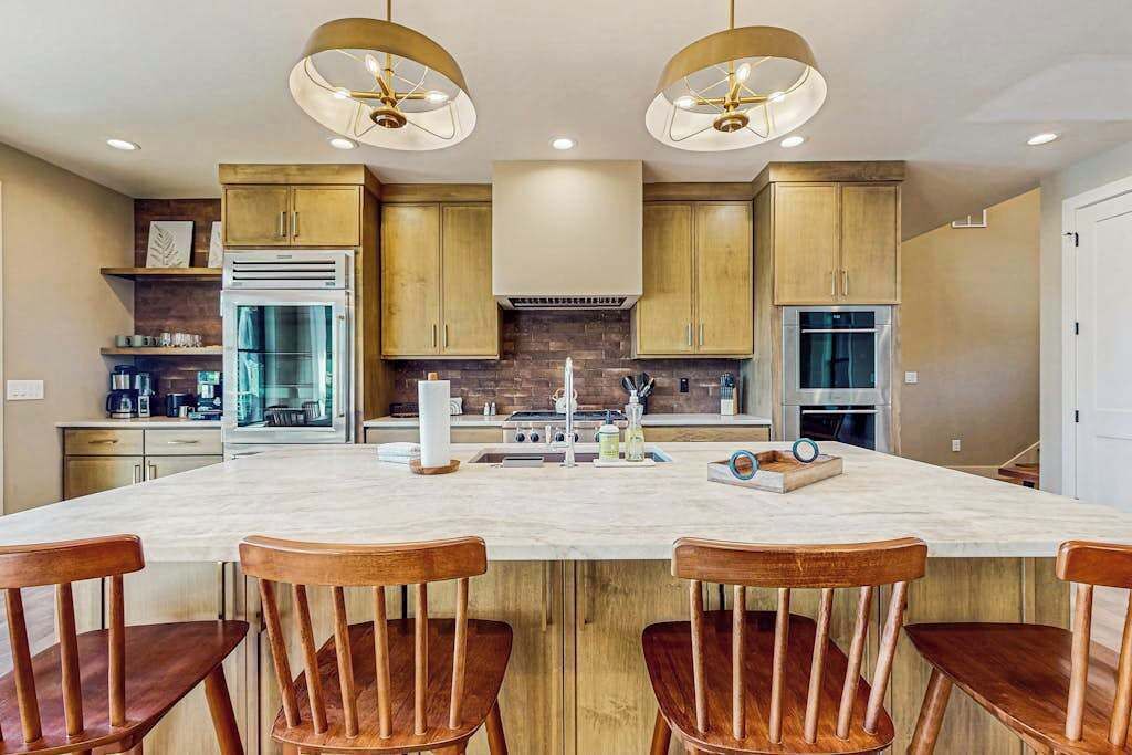 Una cocina con armarios de madera, una isla grande y dos lámparas colgantes.