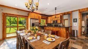 A spacious kitchen with wooden cabinets, a dining table set for breakfast, and a view of the outdoors.