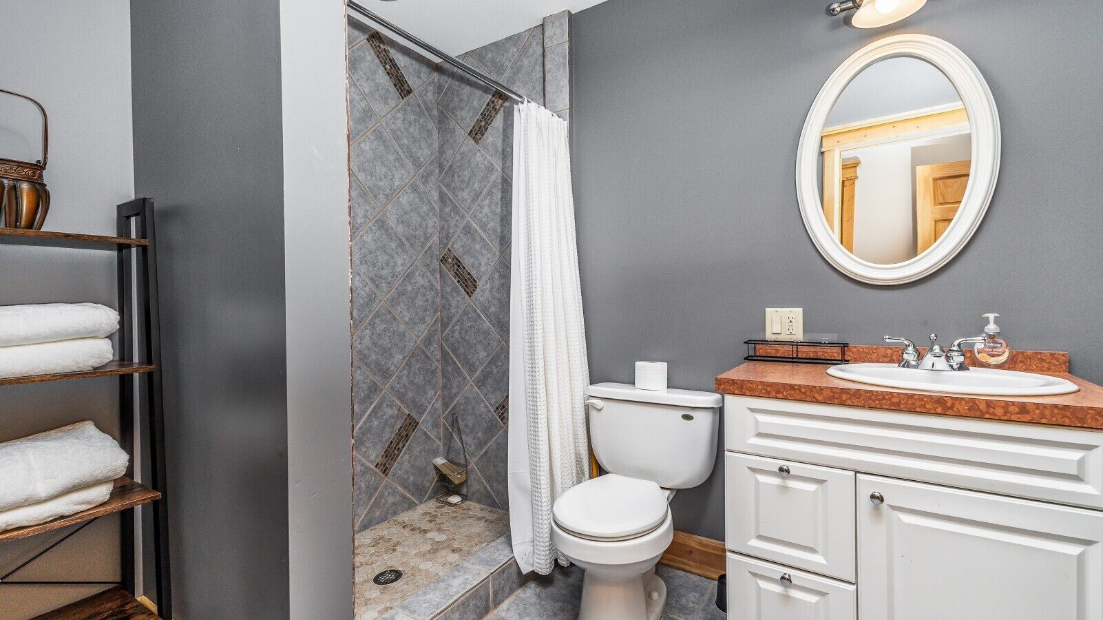 A bathroom with a shower, toilet, sink, and a mirror.