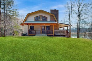 Ein Haus mit Veranda, Schornstein und Blick auf ein Gewässer.